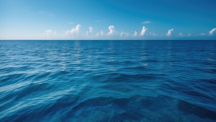 Fototapeta premium Calm water surface of the ocean showing ripples and a small cloud in the blue sky background