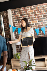 Woman holding chalkboard at gender reveal party, smiling and pointing excitedly