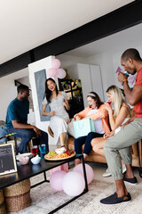 Friends celebrating with gifts and snacks at home, enjoying joyful moments together