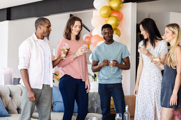 Friends celebrating together at home, enjoying drinks and sharing laughter