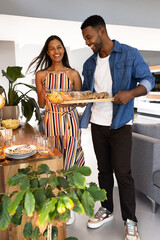 Couple joyfully preparing dinner table with fresh bread and snacks at home