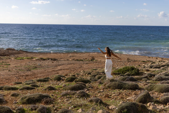 Woman in White Pants Enjoying Freedom by the Sea