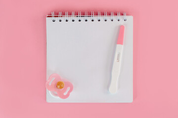 An empty notebook with a pregnancy test on an isolated background, the concept of waiting for a...