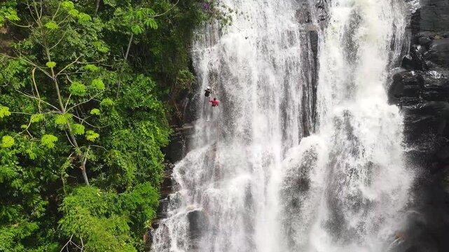 Natural cascade named Cachoeira da Fuma&ccedil;a in Muria&eacute;, Minas Gerais, Brazil. A couple are abseiling down. Zoom out
