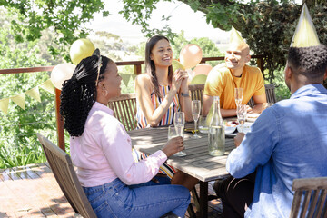 Celebrating outdoors, friends wearing party hats and sharing drinks and laughter