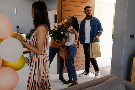 Friends arriving at home with gifts and flowers, ready to celebrate together