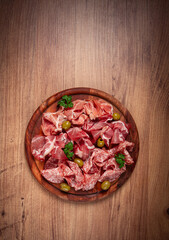 Assortment , sliced meat appetizer, prosciutto, salami and ham, with olives, on a wooden board, breakfast, top view, close-up, no people,