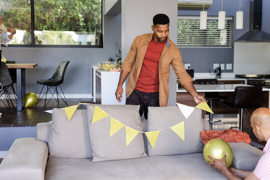 Man decorating living room with gold balloons and bunting for celebration