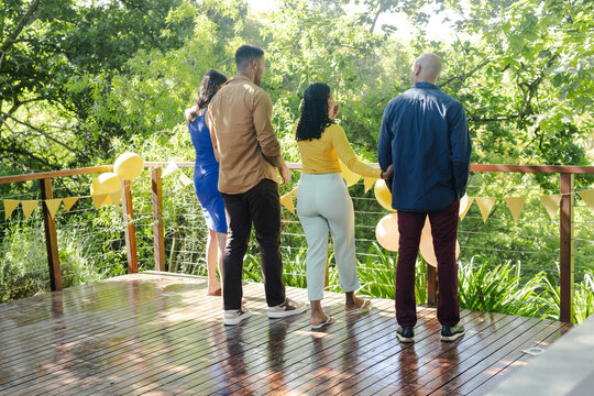 Friends enjoying outdoor celebration on wooden deck surrounded by lush greenery