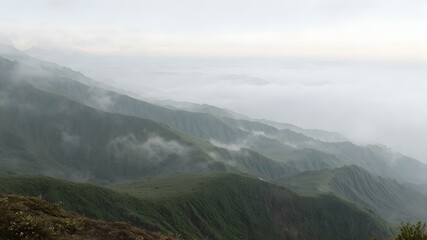 Fototapeta premium Misty Mountain Vista: A breathtaking panorama unfolds, showcasing layered mountain ridges enveloped in a dreamy veil of mist, evoking tranquility and the awe-inspiring beauty of nature.