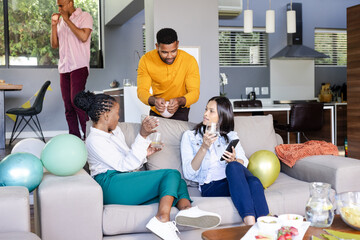 Friends celebrating at home, enjoying drinks and conversation on cozy sofa
