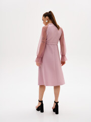 Pregnant girl model in stylish clothes on a colorless background in the studio.