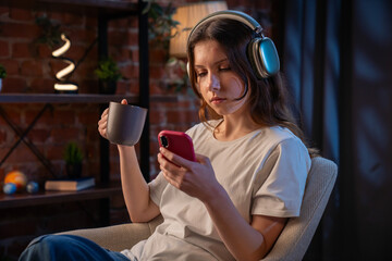 Woman Relaxing with Smartphone, Headphones, and Cup in Cozy Home Environment
