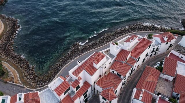 Mediterranean coastal town cadaqu&eacute;s with white buildings, red-tiled roofs sprawling near deep blue waters, captured from overhead perspective