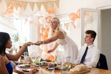 Bride in white dress sharing gift with guests at wedding reception table
