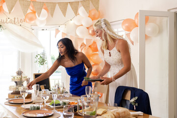 Bride and friend arranging table settings at festive wedding reception