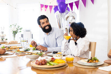 Father and son enjoying festive meal at home with colorful decorations