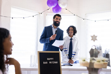 Father and son celebrating Bar Mitzvah, speaking joyfully at decorated party