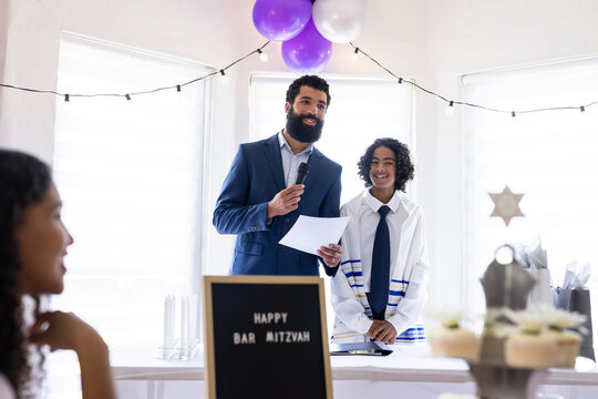 Father and son celebrating Bar Mitzvah, speaking joyfully at decorated party