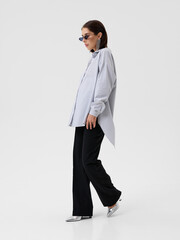 Pregnant girl model in stylish clothes on white background in studio.