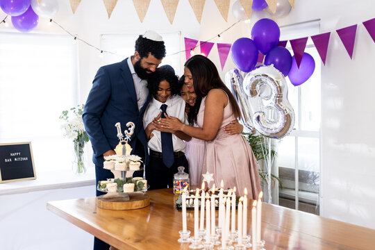 Celebrating bar mitzvah, family sharing joyful moment with cake and decorations together