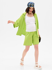 Pregnant girl model in stylish clothes on white background in studio.