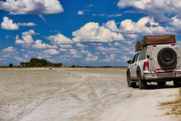 Off-road 4x4 vehicle crossing remote salt pan near Baines Baobabs, Nxai Pan National Park, Botswana. Ideal for: safari travel, self-drive adventure, expedition themes.