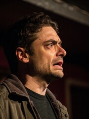 Fototapeta premium Intense speech by a man with furrowed brows and dramatic eyes in a dimly lit background captured closeup