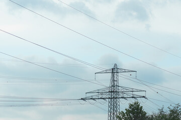Power lines stretch across the sky amidst a cloudy environment in a rural area
