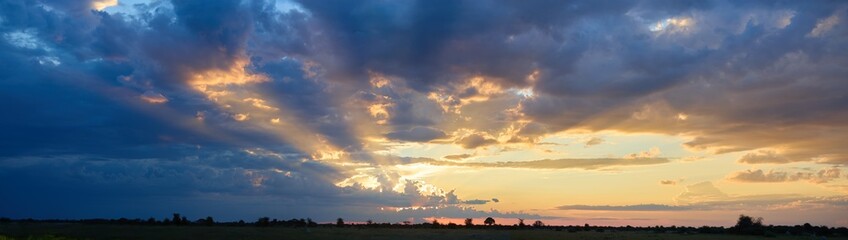 Golden sunset with dramatic sunbeams and colorful clouds over Nxai Pan National Park, Botswana. Ideal for: African landscapes, safari promotions, inspirational nature backgrounds. 