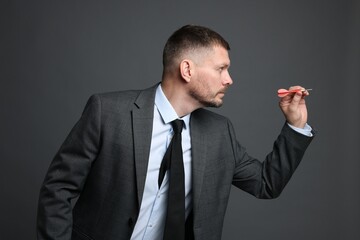 Targeting. Man with dart aiming on grey background
