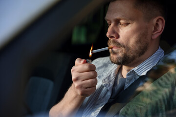 Man lighting cigarette in car, view from outside