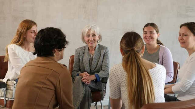Friendly mixed age group of positive women of different nationalities participating together educational course discussing with interest study topics while sitting on chairs in circle in classroom