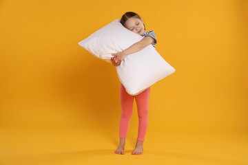 Cute girl with pillow on orange background