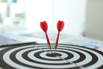 Targeting. Dart board with arrows on table indoors, closeup