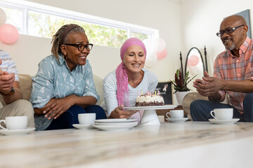 Celebrating birthday, senior friends sharing cake and tea, enjoying joyful moments together