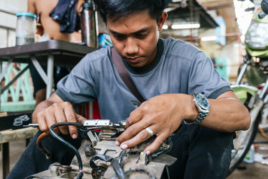 Focused young mechanic repairing a motorbike engine