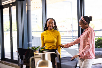 African American women in office smiling and discussing creative business ideas