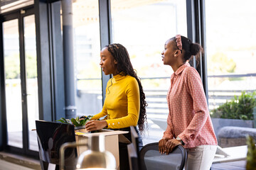 Two women collaborating at office, discussing ideas with enthusiasm and focus
