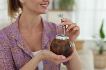Woman with traditional yerba mate tea at home, closeup. Space for text
