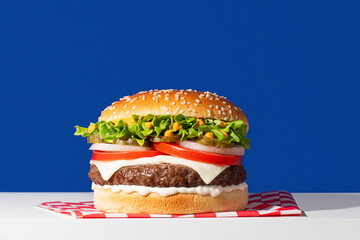 Appetizing classic cheeseburger on a vibrant blue background