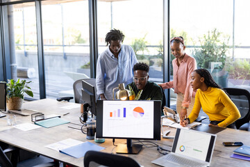 Team collaborating on project, analyzing data on computer screens in modern office