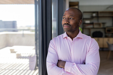 Fototapeta premium Standing by window, businessman in pink shirt contemplating future opportunities