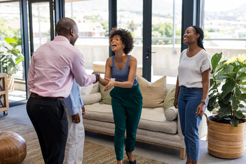 Colleagues greeting each other with handshake in modern office, smiling and engaging
