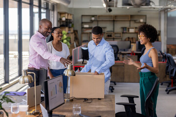 Colleagues unpacking box in modern office, smiling and collaborating on project