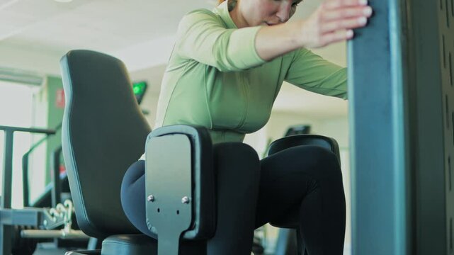 Dedicated female athlete performing targeted inner thigh strength training with professional guidance on specialized gym equipment, focusing on proper technique and muscle development