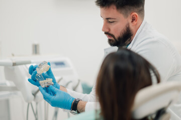 Dentist showing dentures model to patient in clinic