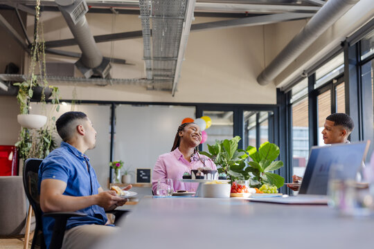 Colleagues enjoying lunch and conversation in modern office break room