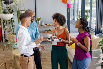 Colleagues celebrating birthday with cake and drinks in modern office setting