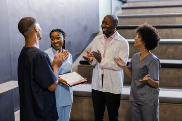 Celebrating in hospital stairwell, medical team clapping for colleague receiving award
